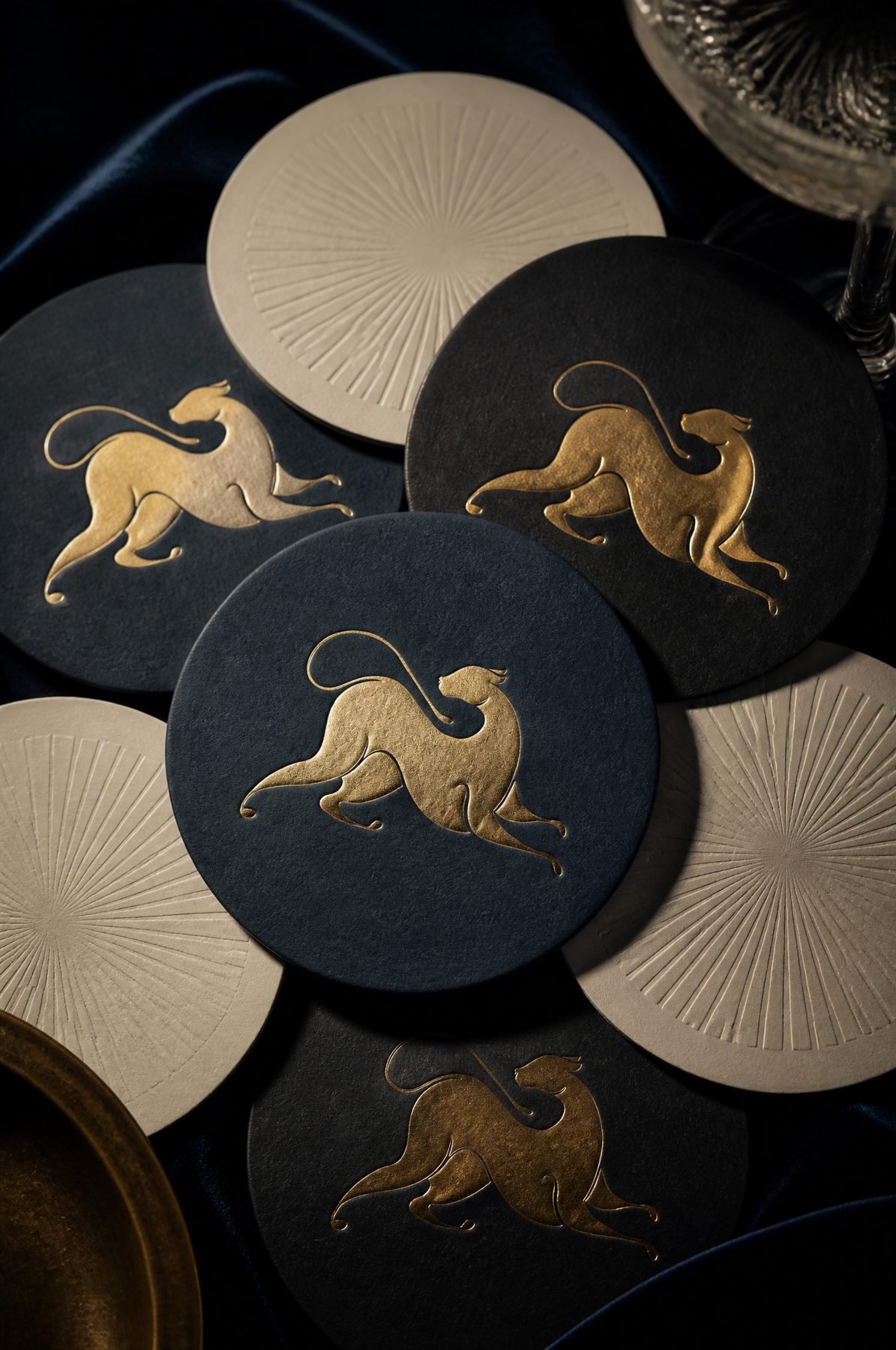 Navy and ivory coasters with the gold-foil leopard and a debossed sunburst.